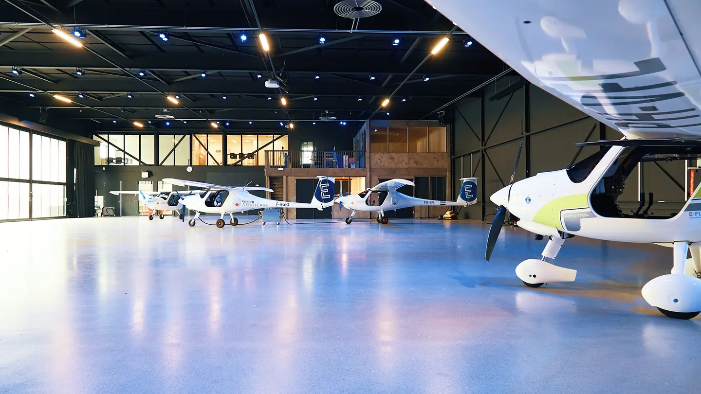 Lege, verlichte hangar met elektrische vliegtuigen aan de zijkant