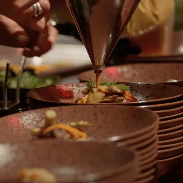 Kok spuit garnering op borden met een gerecht in donkere kommen