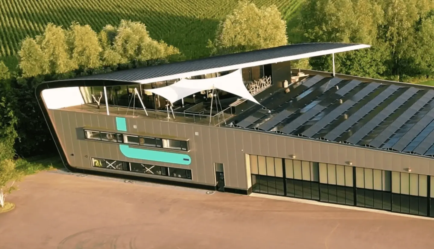 Luchtfoto van het E-Deck-gebouw met dakterras, schaduwdoeken en zonnepanelen