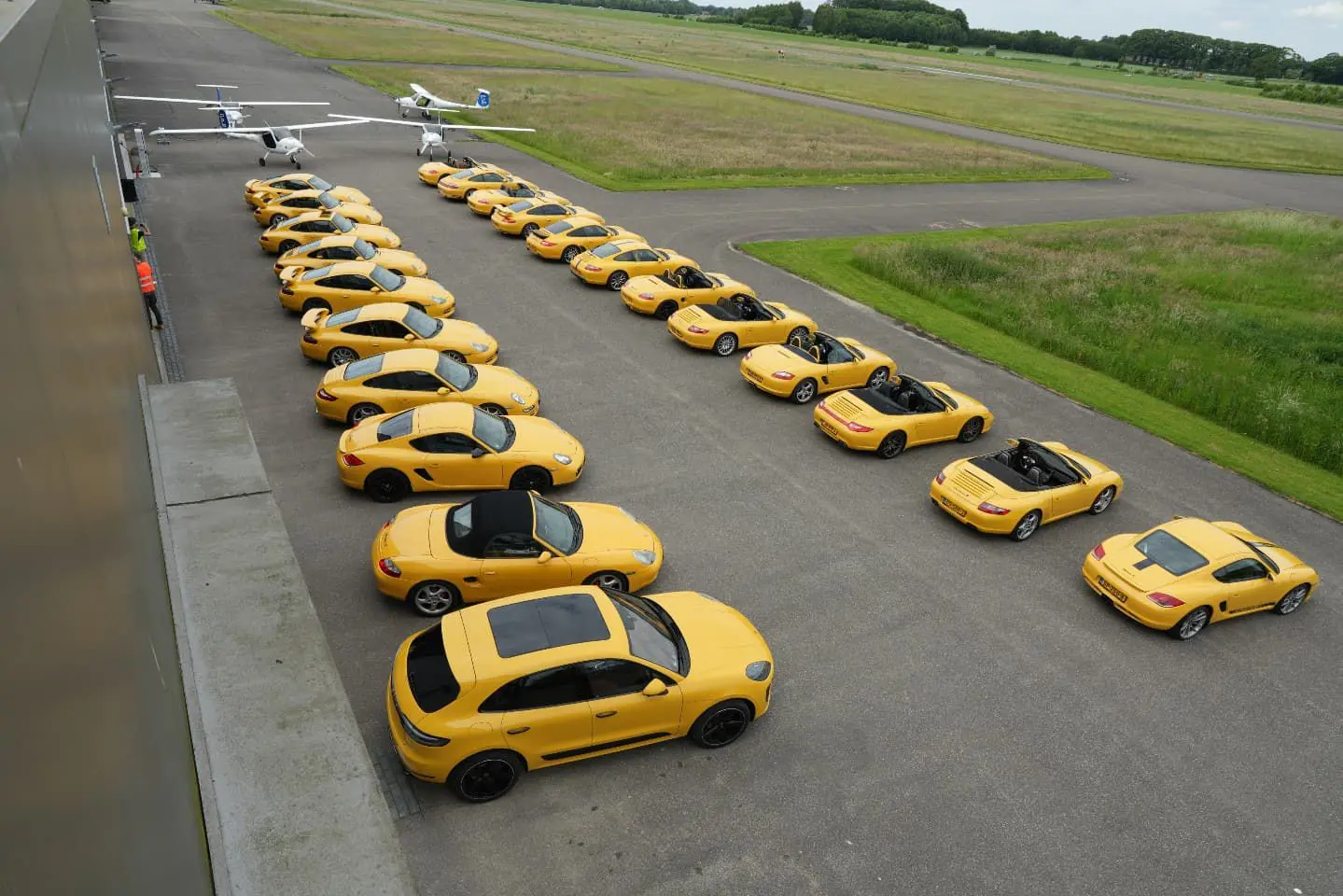 Rij gele Porsches op het platform naast de landingsbaan van Teuge