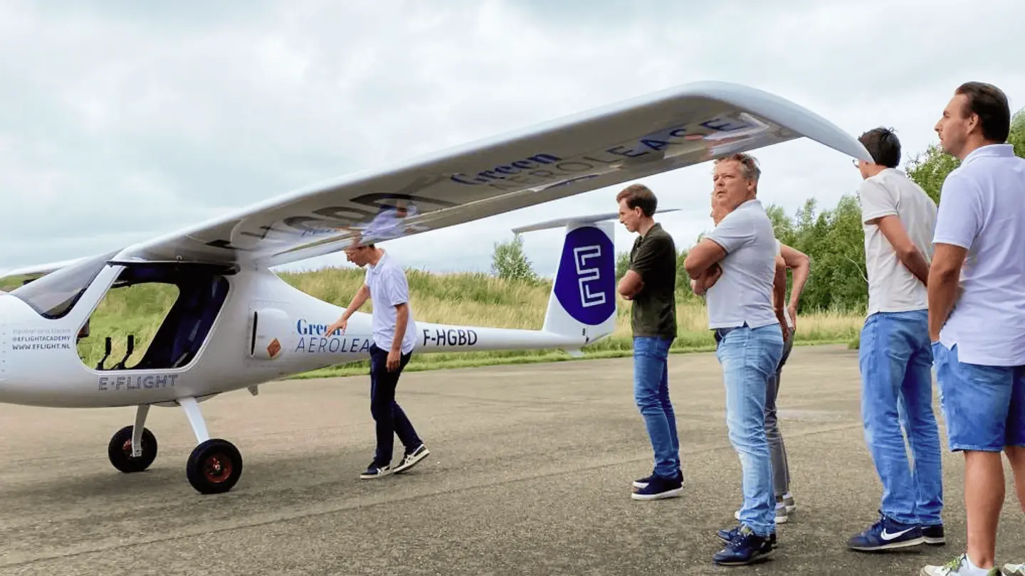 Groep bezoekers luistert naar uitleg bij een elektrisch vliegtuig van E-Flight