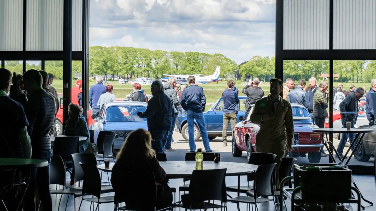 Gasten bekijken klassieke auto's op het platform door de geopende hangar