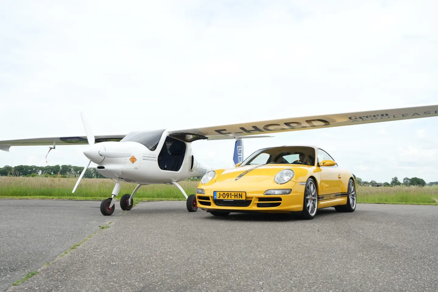 De Pipistrel Velis Electro naast een Porsche in Speedgelb.