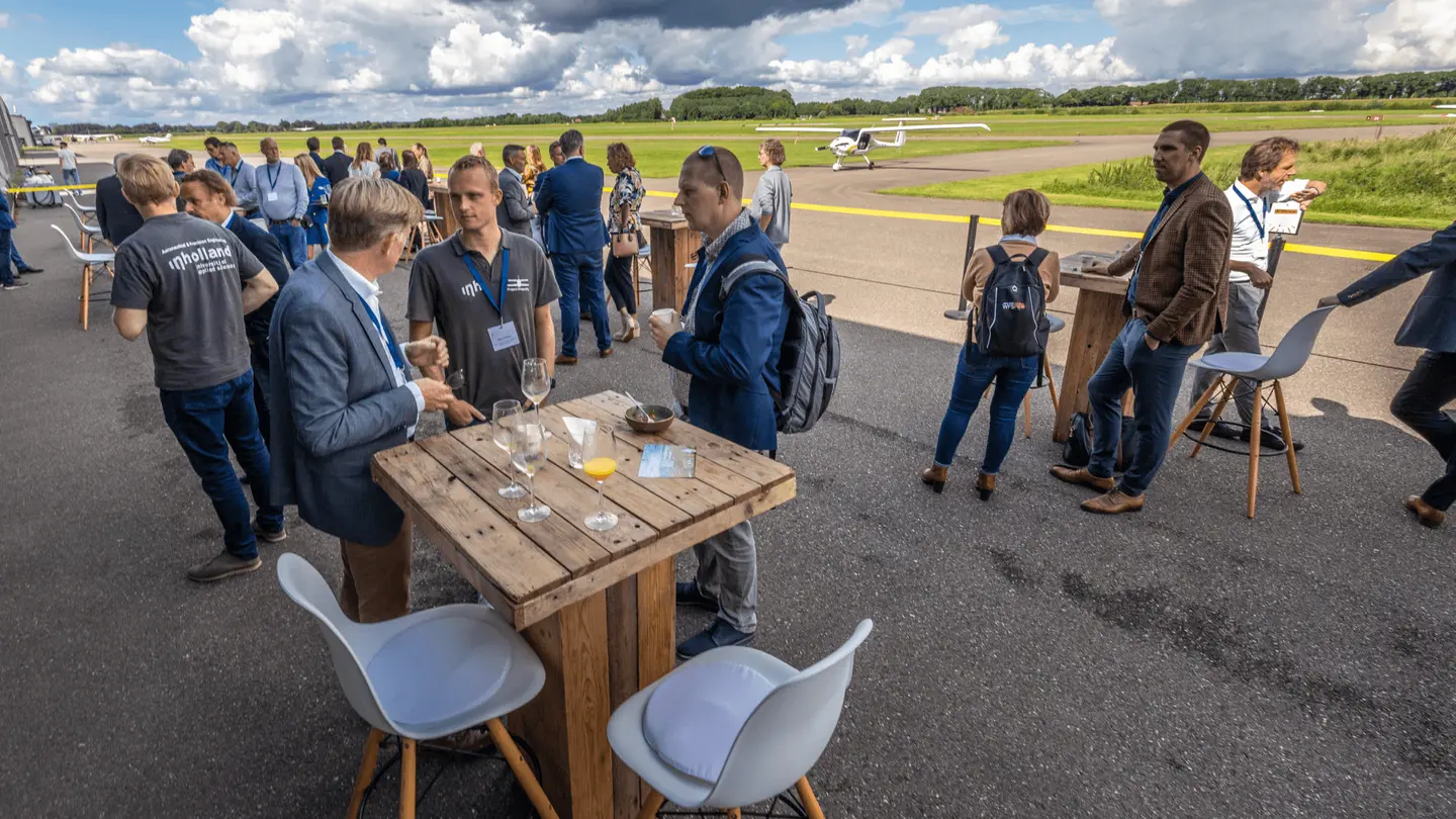 Bezoekers in gesprek bij een houten statafel op het platform