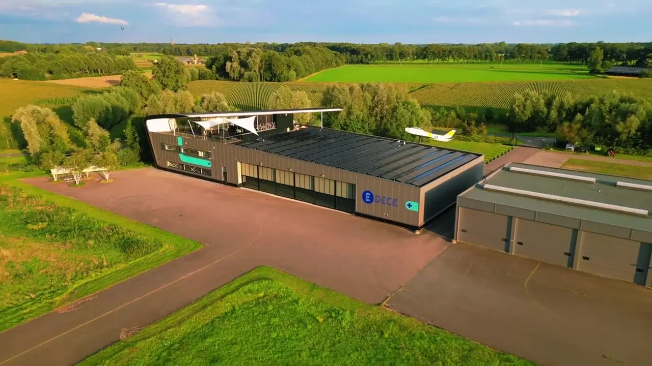 Luchtbeeld van het E-Deck-gebouw met platform en omliggende weilanden