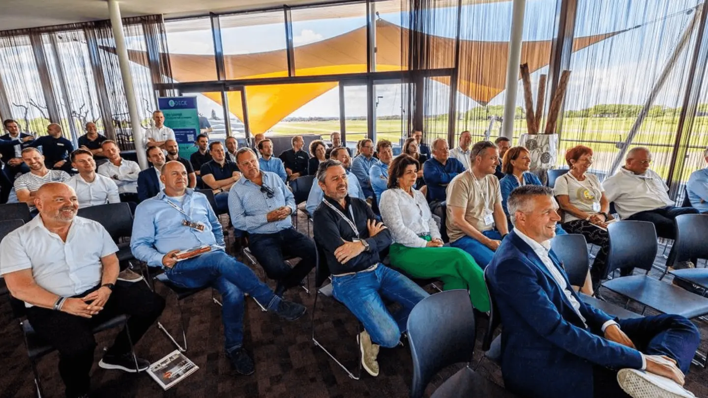 Publiek luistert in de Sky Lounge naar een presentatie