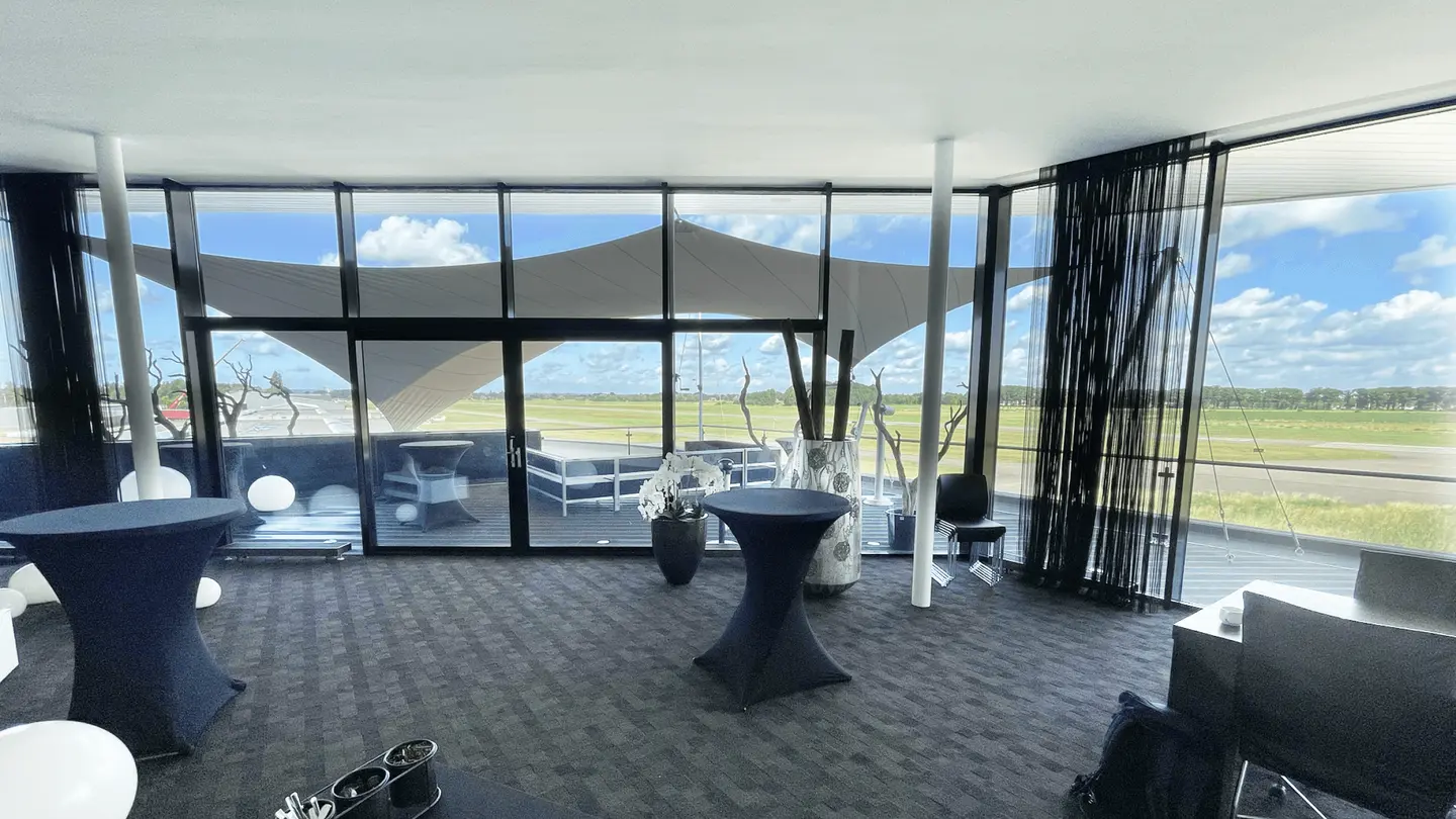 Lege Sky Lounge met statafels en uitzicht op het vliegveld door glazen wanden