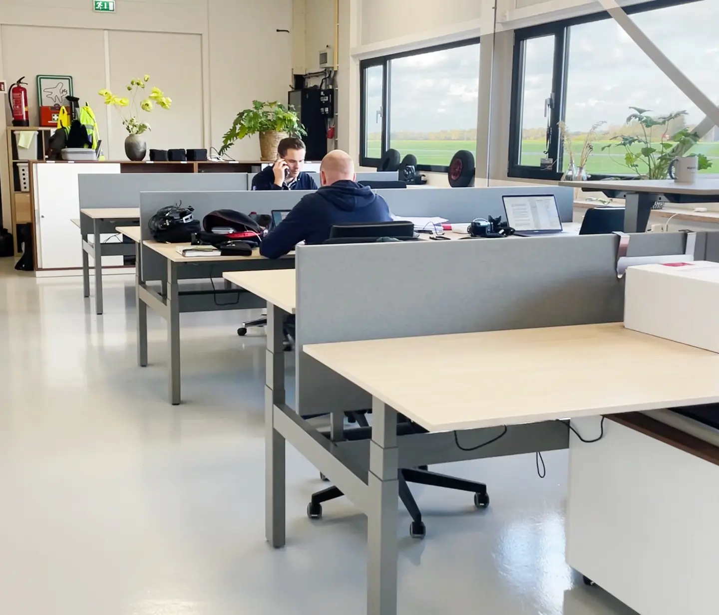 Kantoorwerkplekken met bureaus en uitzicht naar buiten op de E-Campus