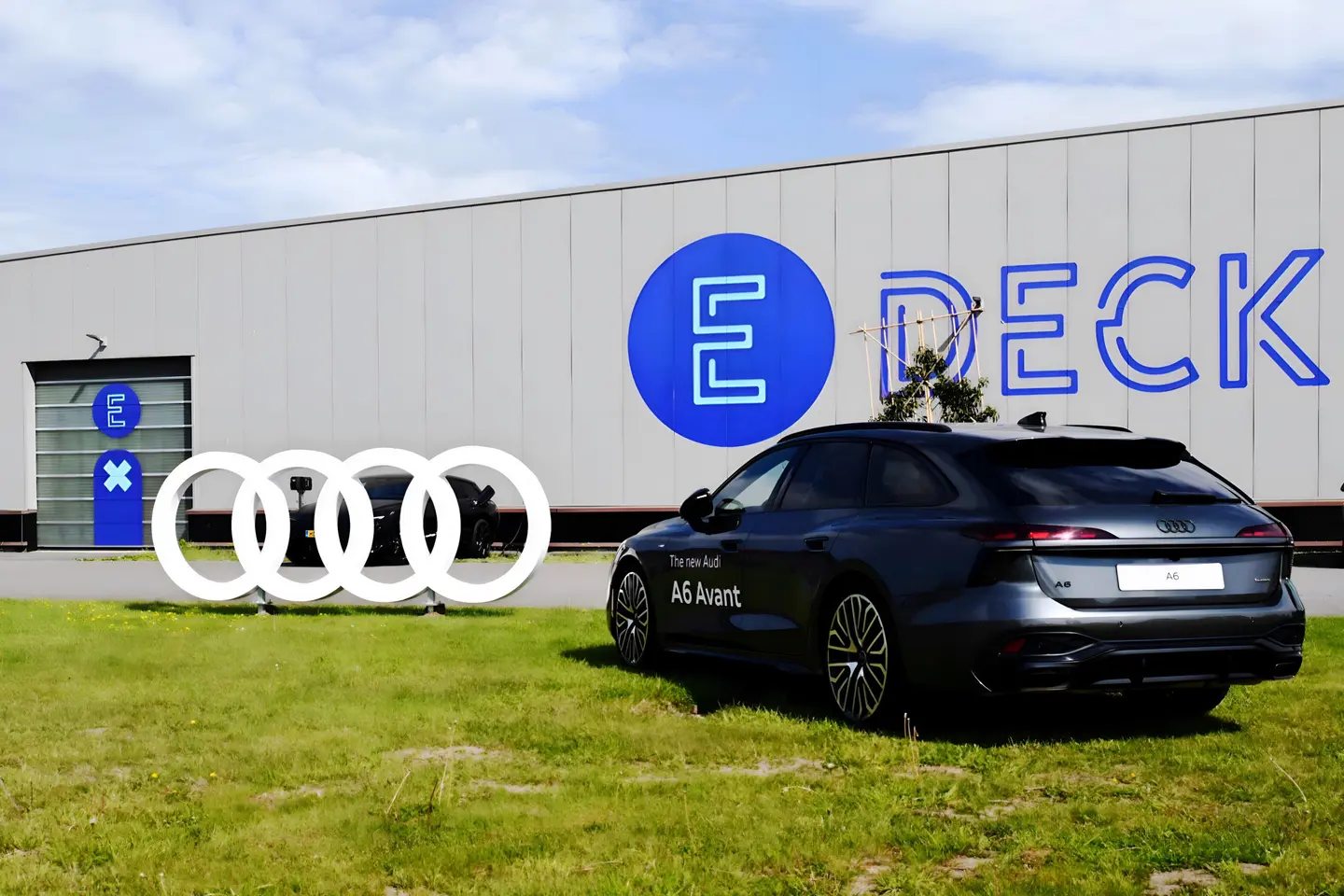 Audi geparkeerd op het gras voor de hangar met het E-Deck-logo