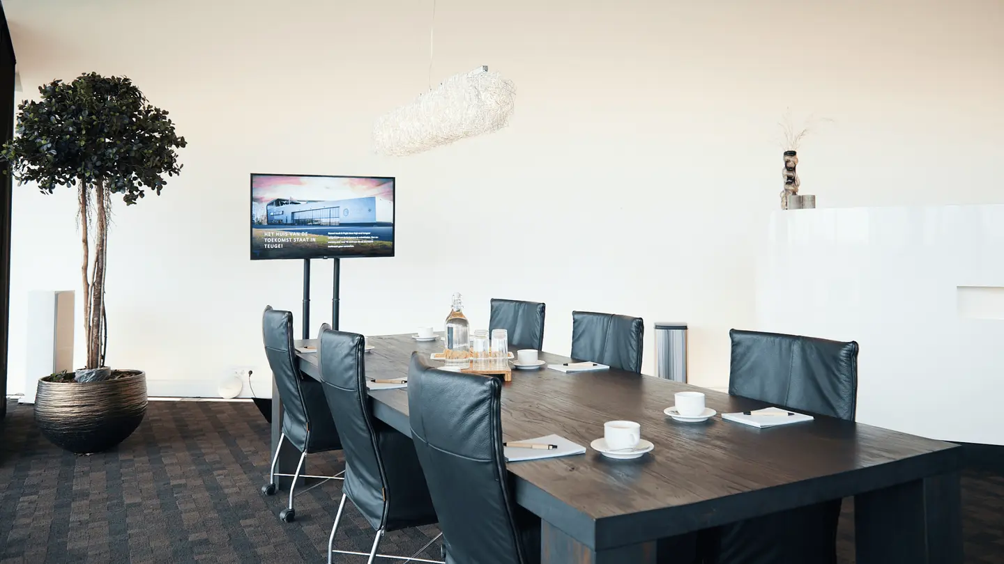 Sky Lounge met donkere vergadertafel, stoelen en tv-scherm