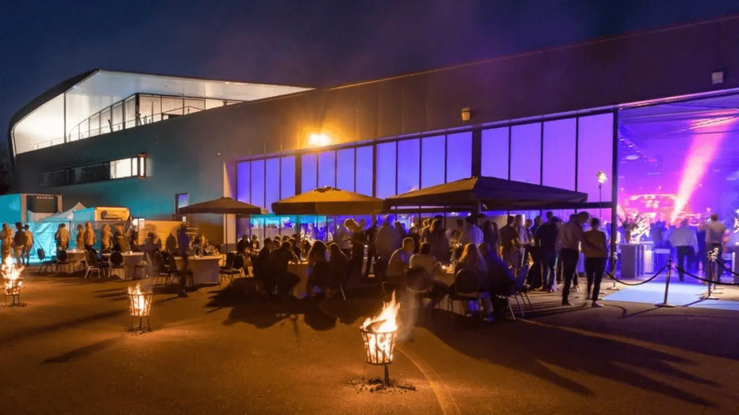 Avondevent bij de verlichte hangar met vuurkorven en parasols