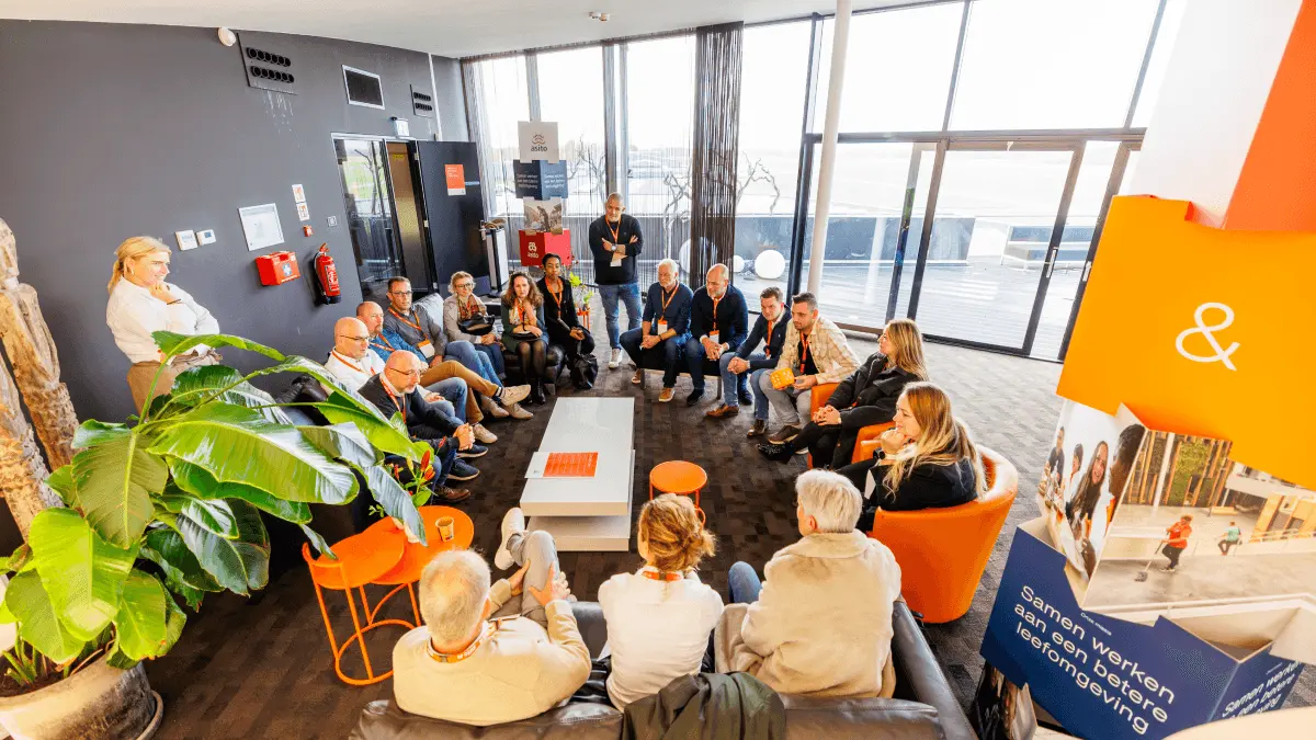 Groep in gesprek in de lounge met oranje en witte banken