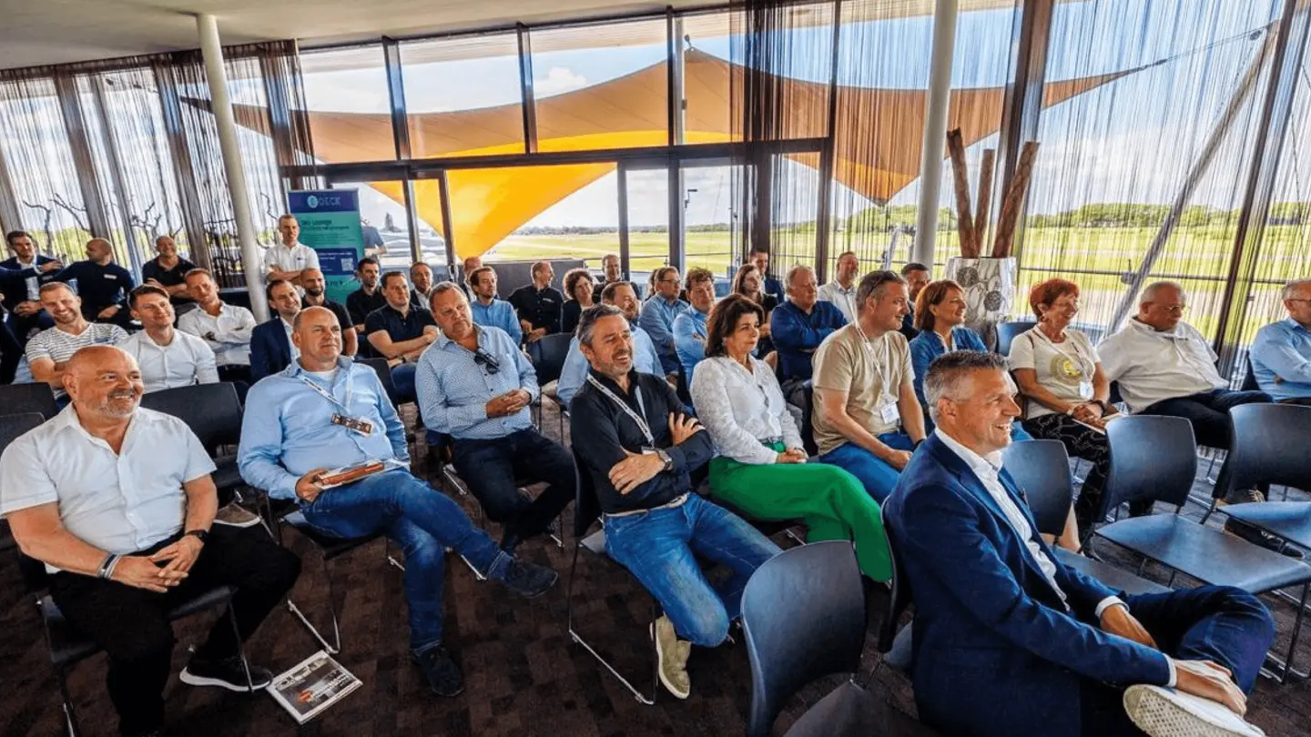 Publiek luistert in de Sky Lounge naar een presentatie