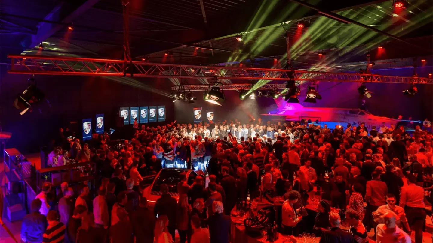 Volle hangar met feestende gasten onder rode en groene showverlichting