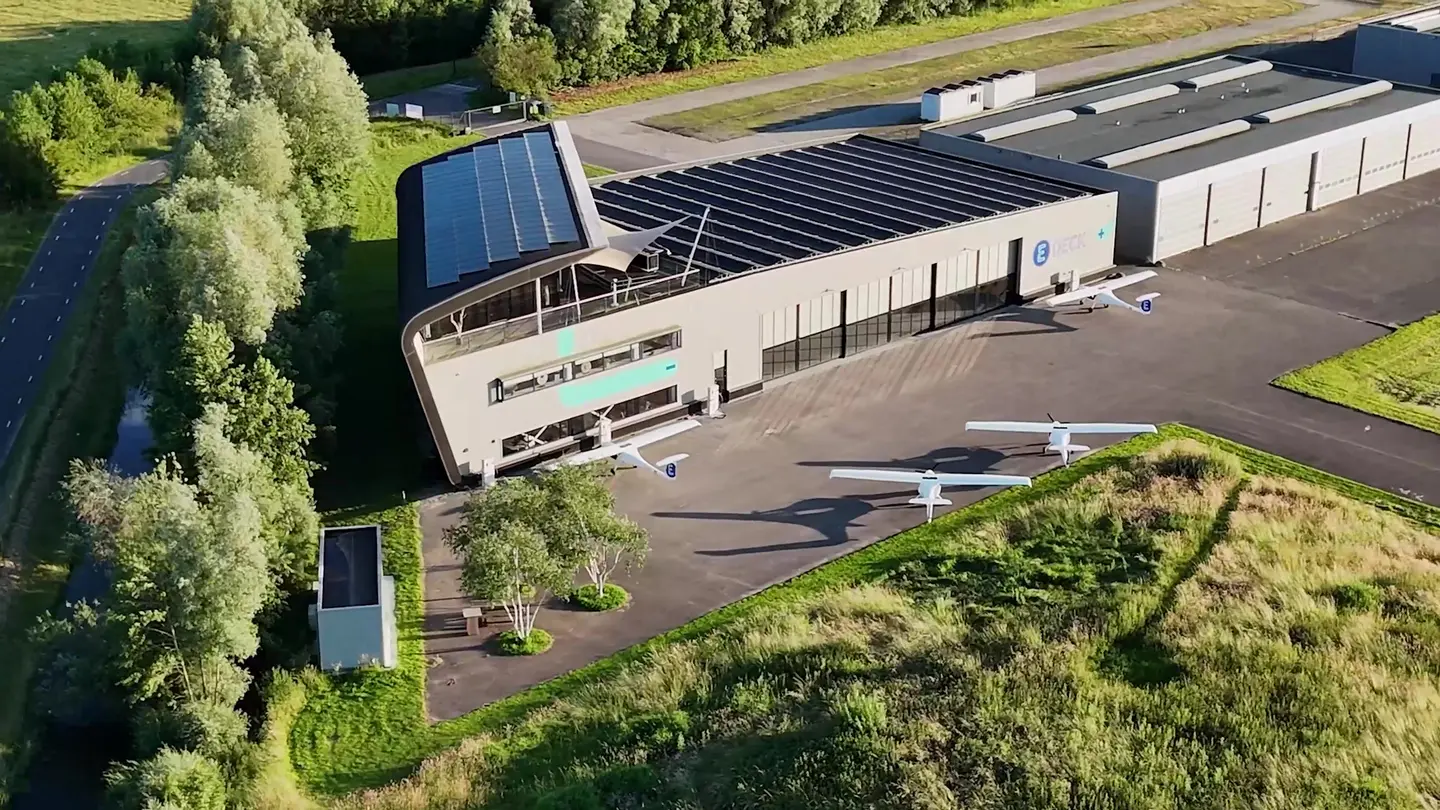 Luchtbeeld van het E-Deck-gebouw met zonnepanelen en vliegtuigen op het platform